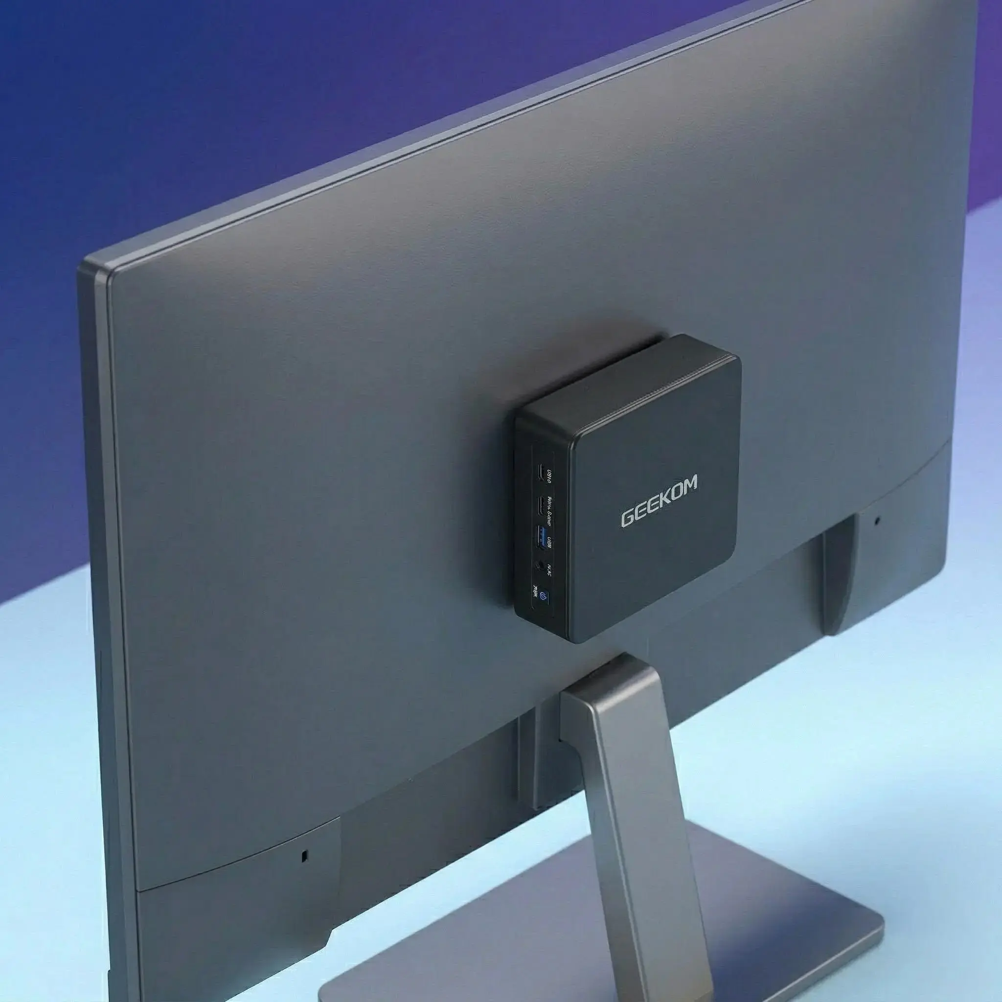 Mini PC GEEKOM montada en soporte VESA detrás de monitor